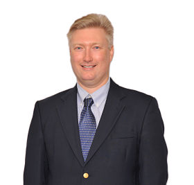Photo of Jason Anglin smiling and wearing a suit and tie.