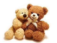 A tan teddy bear leaned up against a brown teddy bear wearing a tan bow