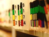 A row of medical files with multicolored tabs sticking out of them and two specific files pulled out from the rest that read 9 1 7 2 and 9 1 7 4 in descending order