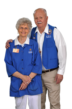 An smiling older man with his arm around a smiling older woman